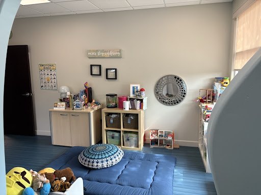 A calm room with a floor futon, a mandala cushion, and shelves of things to explore