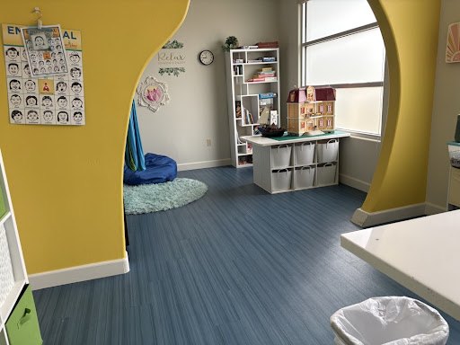 The relax corner — a hanging blue silk and bean bag beside the feelings chart and a dollhouse